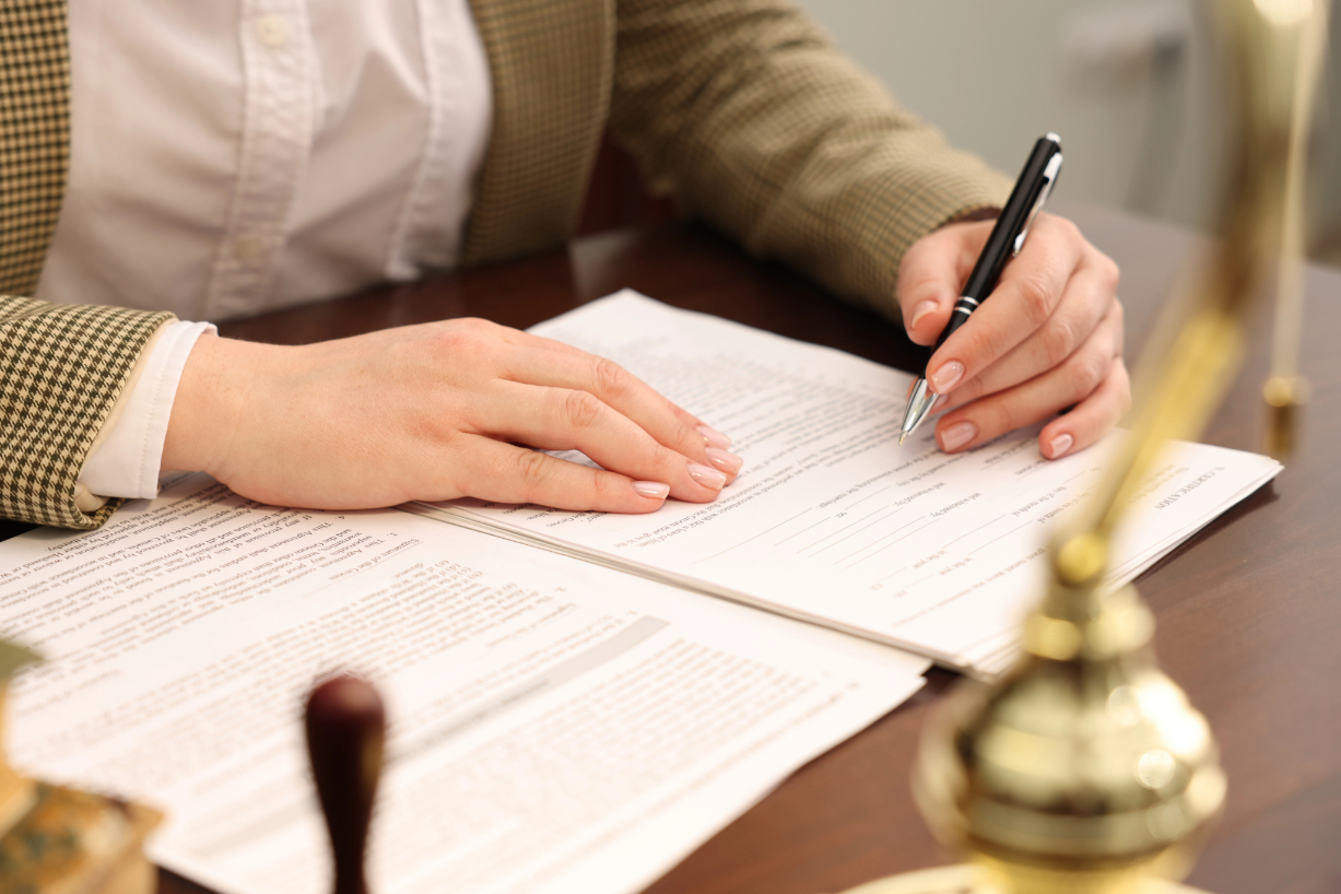 Notary signing document at table in office, closeup Notary signing document at table in office, closeup
